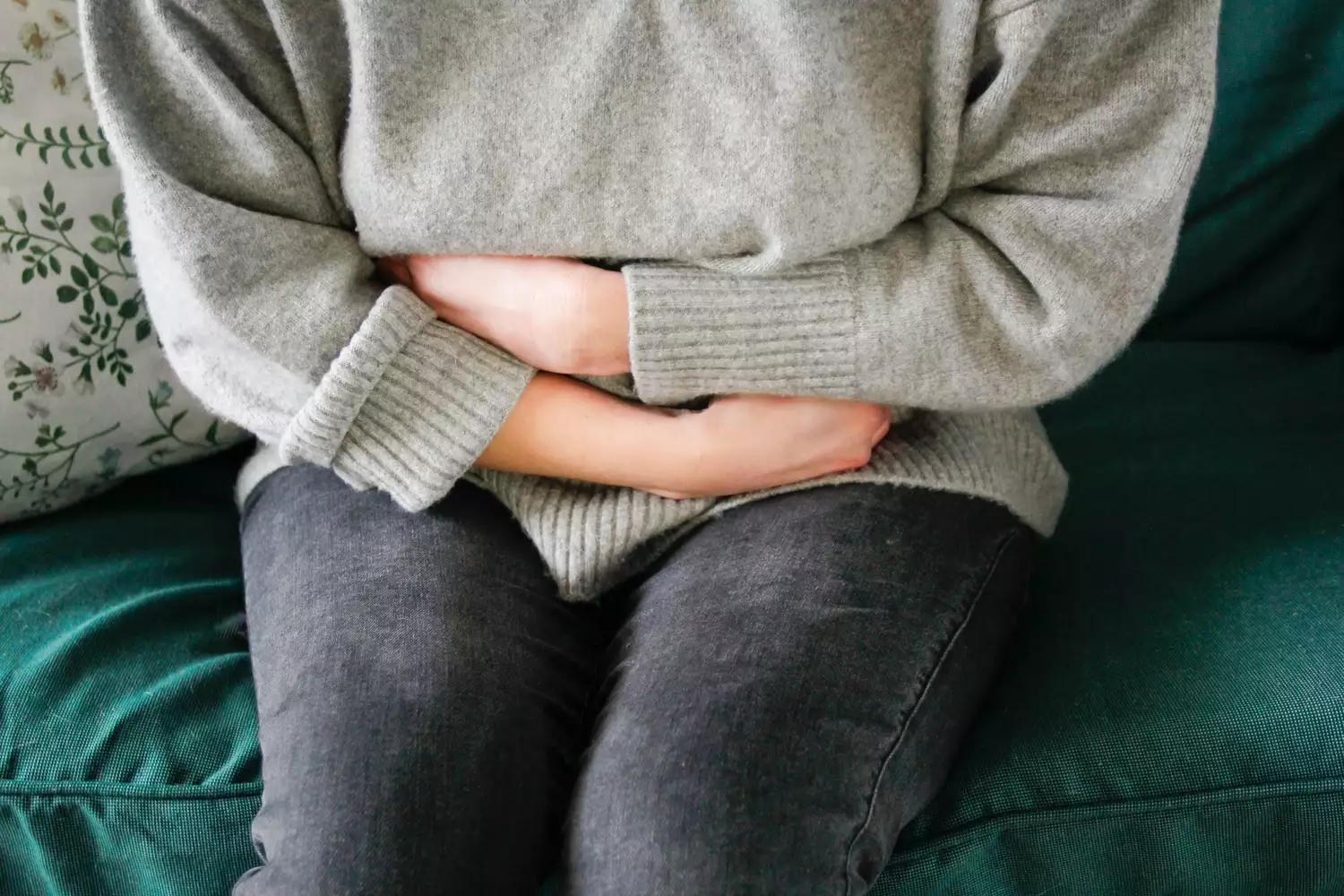 A person sitting on a sofa experiencing bloating after eating.