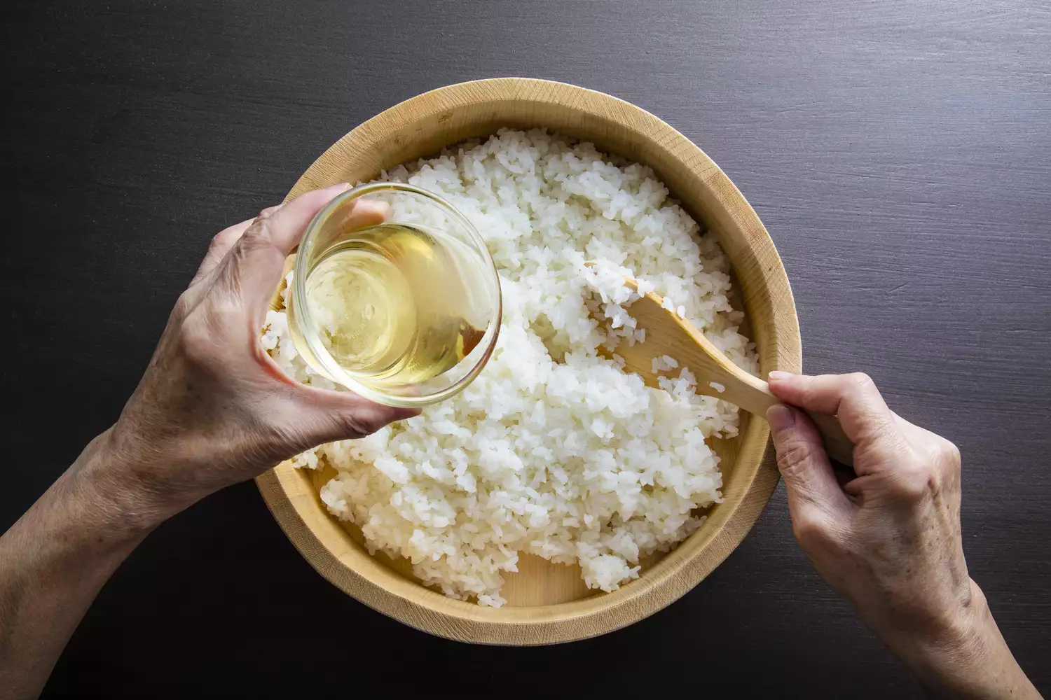 Pouring rice vinegar into a bowl of white rice