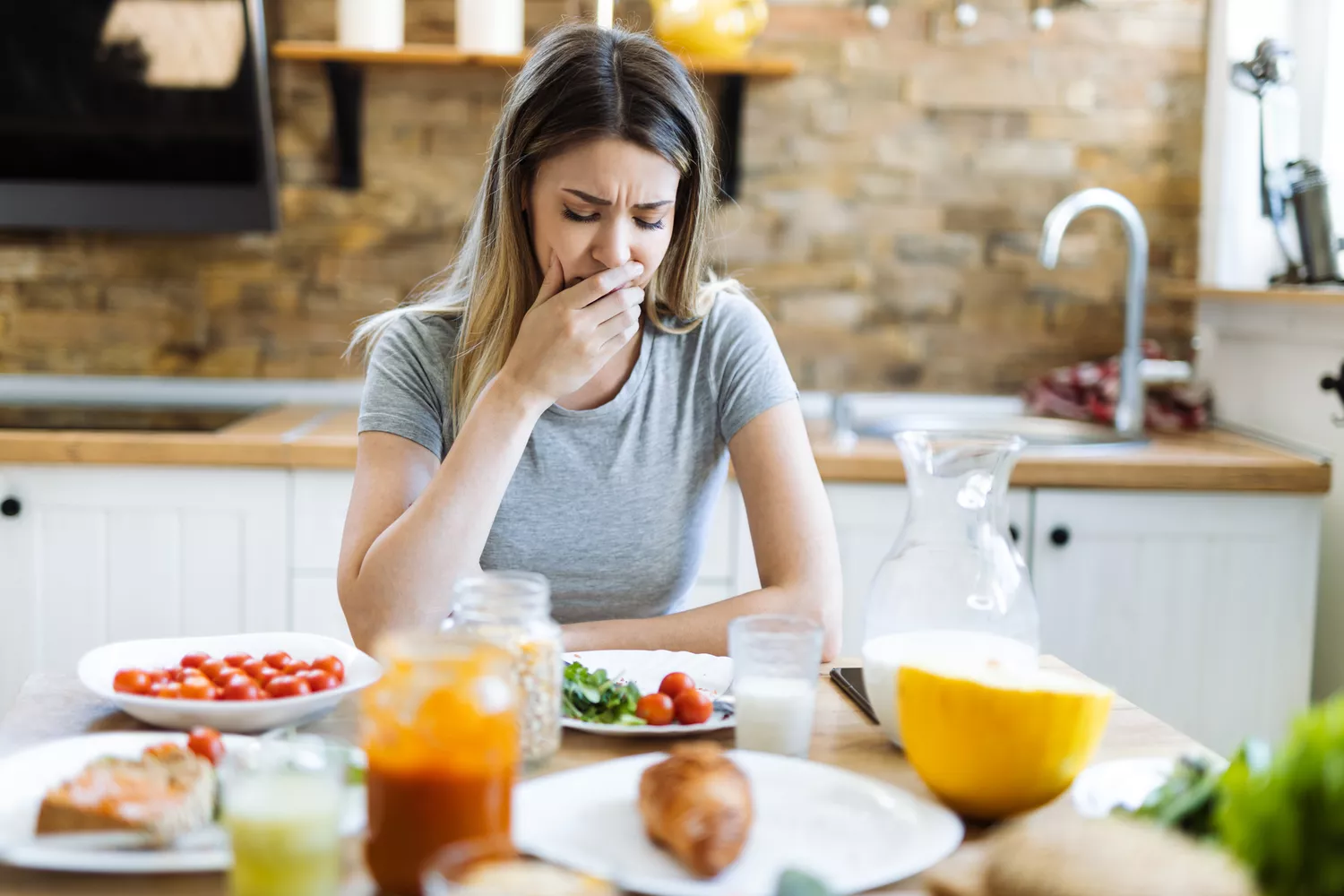 Young woman feeling nausea during breakfast time at dining table